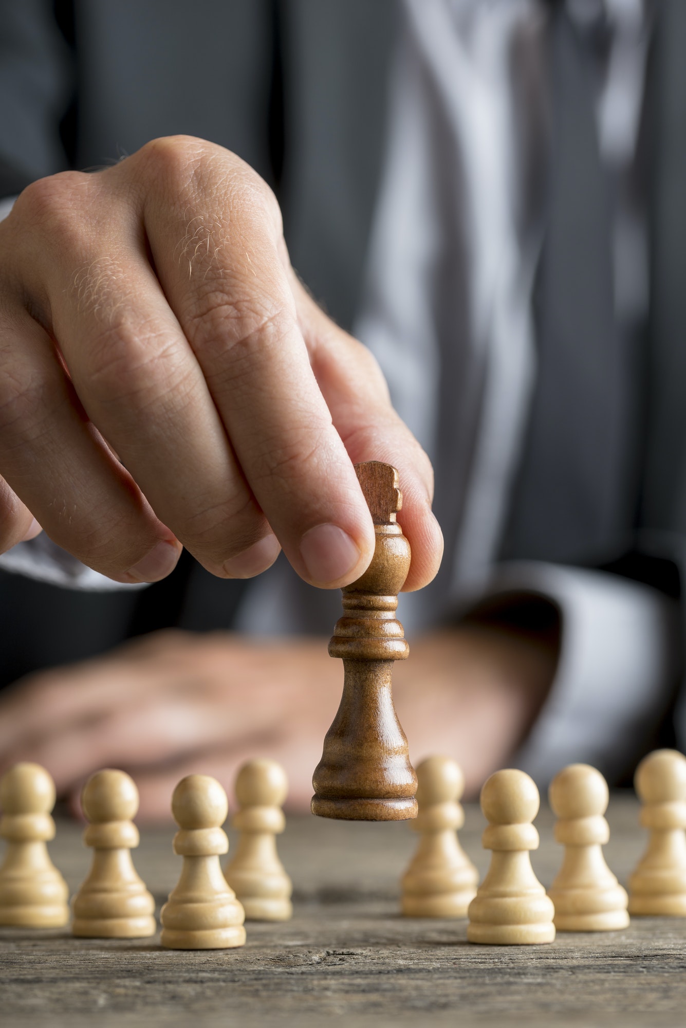 Businessman playing chess moving black king piece lifting it up