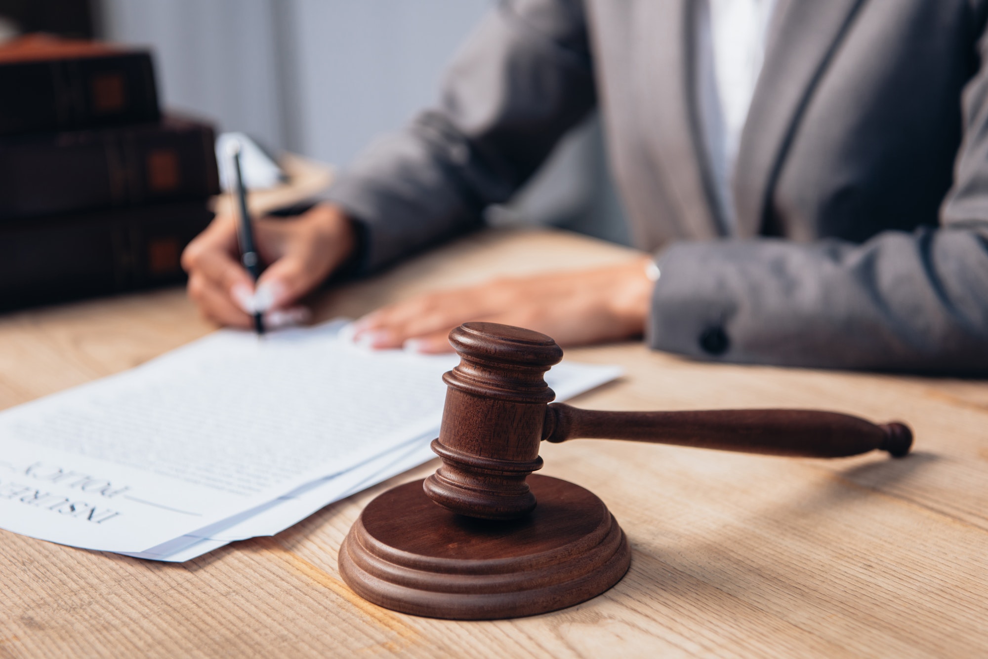 cropped view of judge signing insurance policy document near gavel